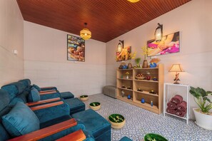 Un'area relax moderna con un divano blu, scaffali in legno con oggetti decorativi e un pavimento piastrellato.