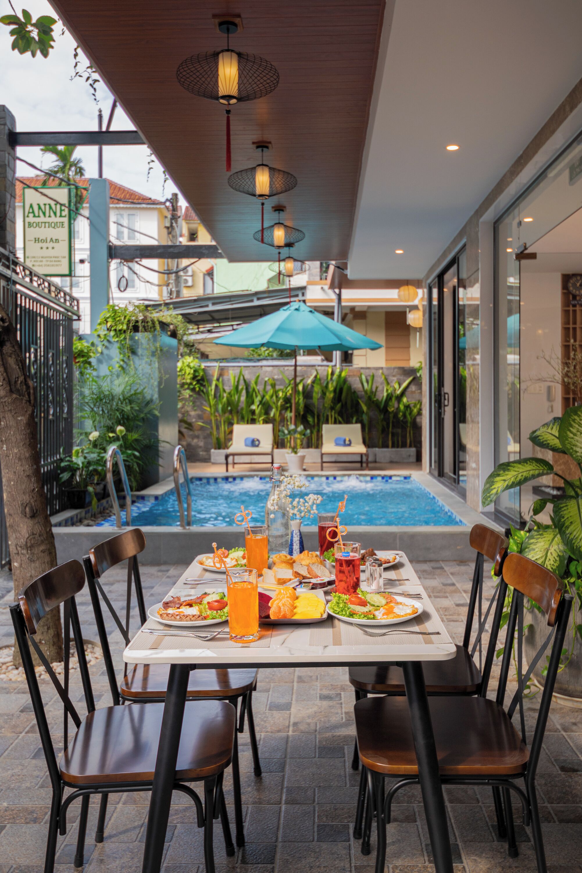 Ein Essbereich im Freien mit Pool, Stühlen und einem Tisch, gedeckt für eine Mahlzeit.