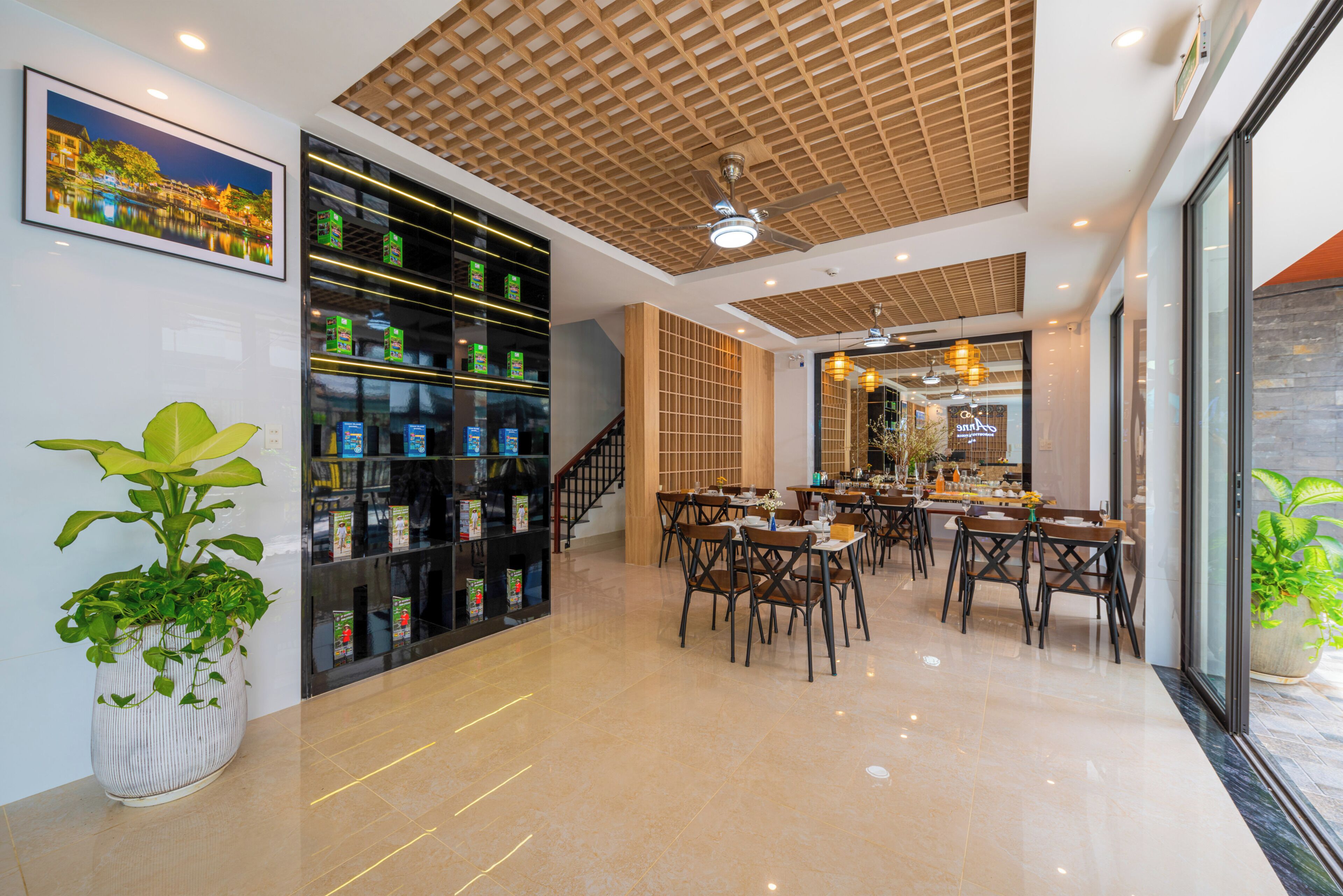 A modern dining area with a high ceiling, a staircase, and a view of the restaurant through glass doors.