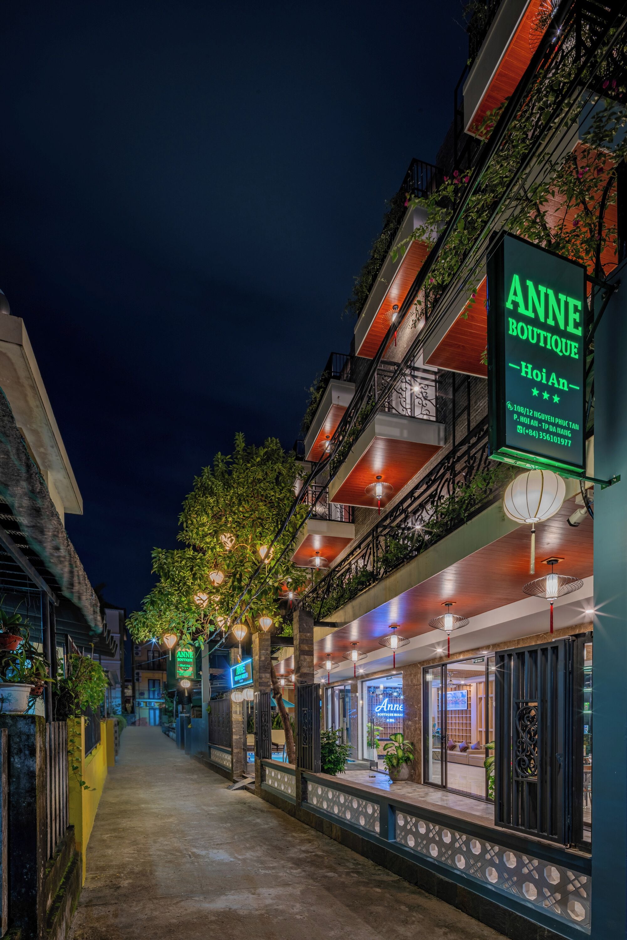 Nachtsicht einer Straße mit einem Boutique-Hotel namens 'Anne Boutique' und einer Neonreklame.
