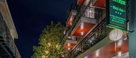 A nighttime street view with a boutique hotel named 'Anne Boutique' with a neon sign.