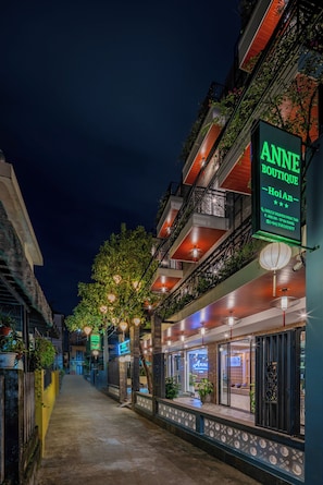 Vista nocturna de una calle con un hotel boutique llamado 'Anne Boutique' y un letrero de neón.