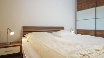 A neatly made bed with white bedding, a wooden headboard, and bedside lamps.