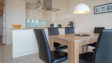 A modern kitchen with a dining area, featuring a wooden table and black chairs.