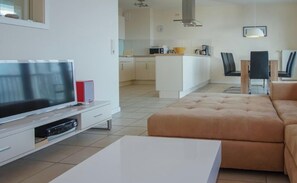 A modern living room with a flat-screen TV, a beige sofa, and a white coffee table. - Holiday Apartment With 2 Bedrooms (Grossenbrode)