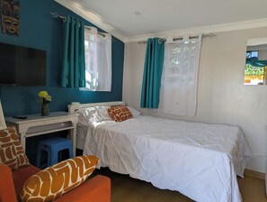 A bedroom with a bed, a desk, a chair, and a TV.