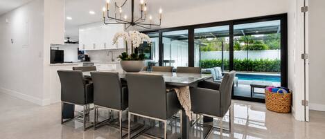 Una cocina moderna con comedor, ventanas amplias y vista a una piscina.