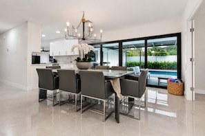 A modern kitchen with a dining area, large windows, and a view of a swimming pool. - Terra Nova at Delray Beach - Minutes To Beach & Atlantic Avenue (Delray Beach)