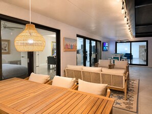 Ein modernes Interieur mit Essbereich, Sofagarnitur und großem Fenster mit Blick auf eine Küche.