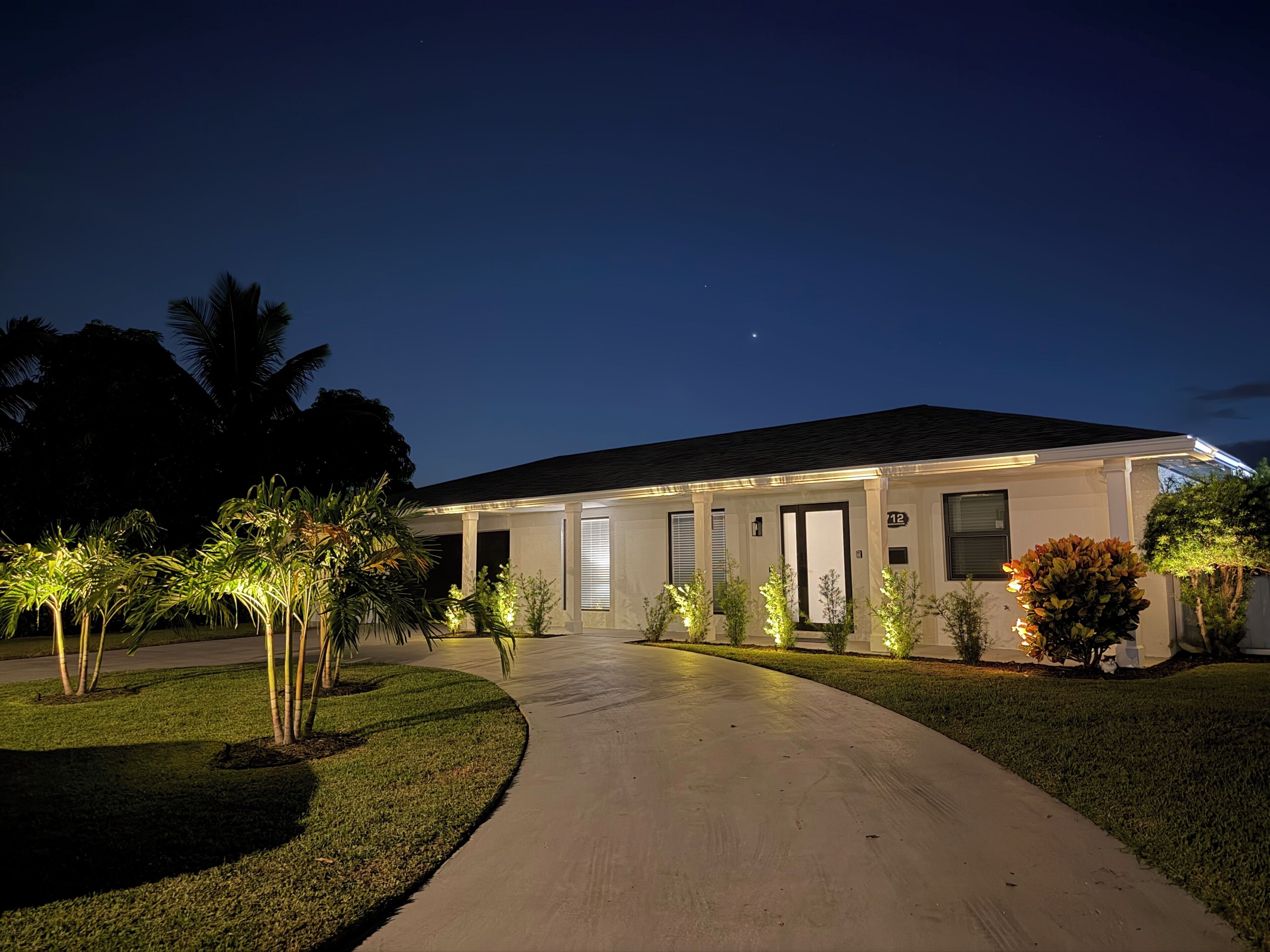 A residential house with a driveway, well-lit exterior, and a clear night sky. - Terra Nova at Delray Beach - Minutes To Beach & Atlantic Avenue (Delray Beach)