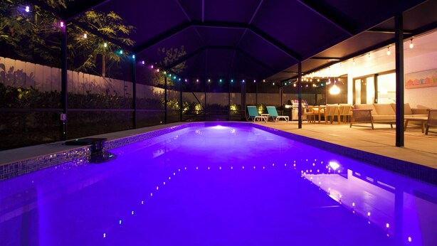 Une piscine extérieure dotée d’un espace couvert, entourée de chaises longues et d’une terrasse avec des tables.