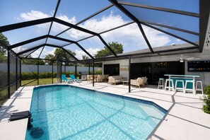 Une piscine extérieure couverte, dotée de chaises longues et d’un espace bar.