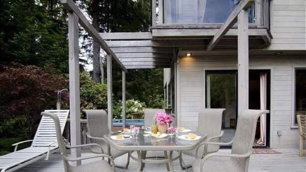 Una terraza con mesa y sillas, un área techada y una casa al fondo.