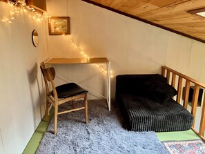 A cozy room with a wooden desk, a black chair, a black cushioned bench, a small rug, and a picture on the wall. - Moonstone Sanctuary-Queen w/Deluxe Loft, Magical Forest View in Spacious Home (Trinidad)