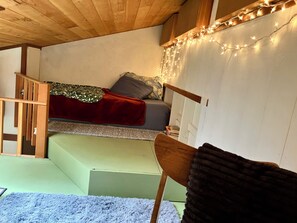 A small, cozy room with a bunk bed, a wooden ladder, a small table, and a chair. - Moonstone Sanctuary-Queen w/Deluxe Loft, Magical Forest View in Spacious Home (Trinidad)