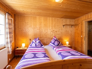 A wooden-paneled room with two beds, each with a headboard, and bedside lamps.