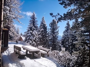 A snow-covered outdoor area with a picnic table and a wooden fence.