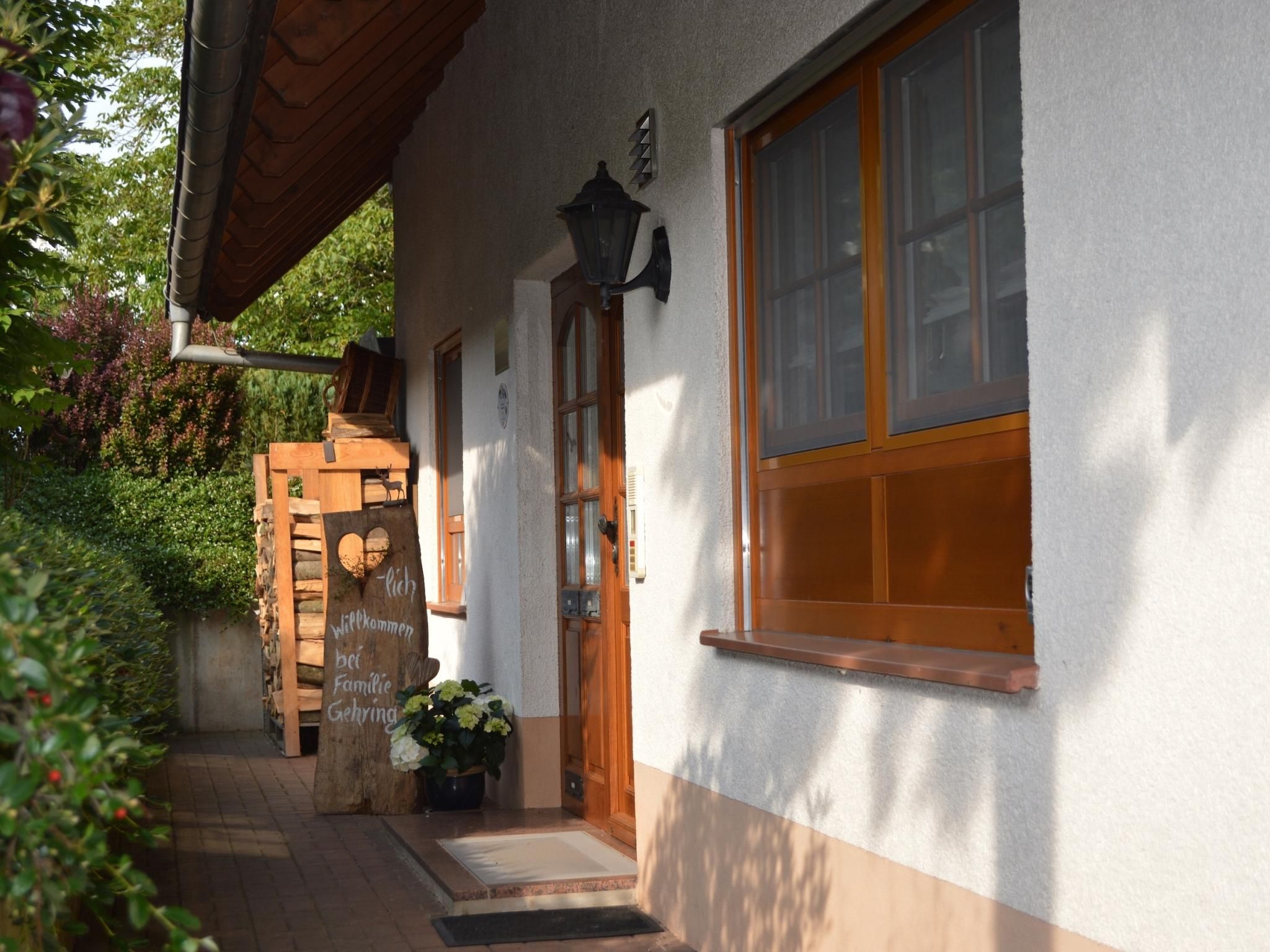 Une maison avec une porte d’entrée en bois, une pancarte de bienvenue et une fenêtre.