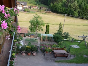 A garden with potted plants, a wooden bench, and a green structure. - Apartment in the Black Forest with a balcony (Schuttertal)