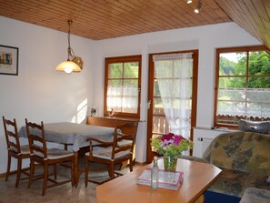 A cozy room with a wooden table, chairs, a sofa, and a window with a view of greenery. - Apartment in the Black Forest with a balcony (Schuttertal)