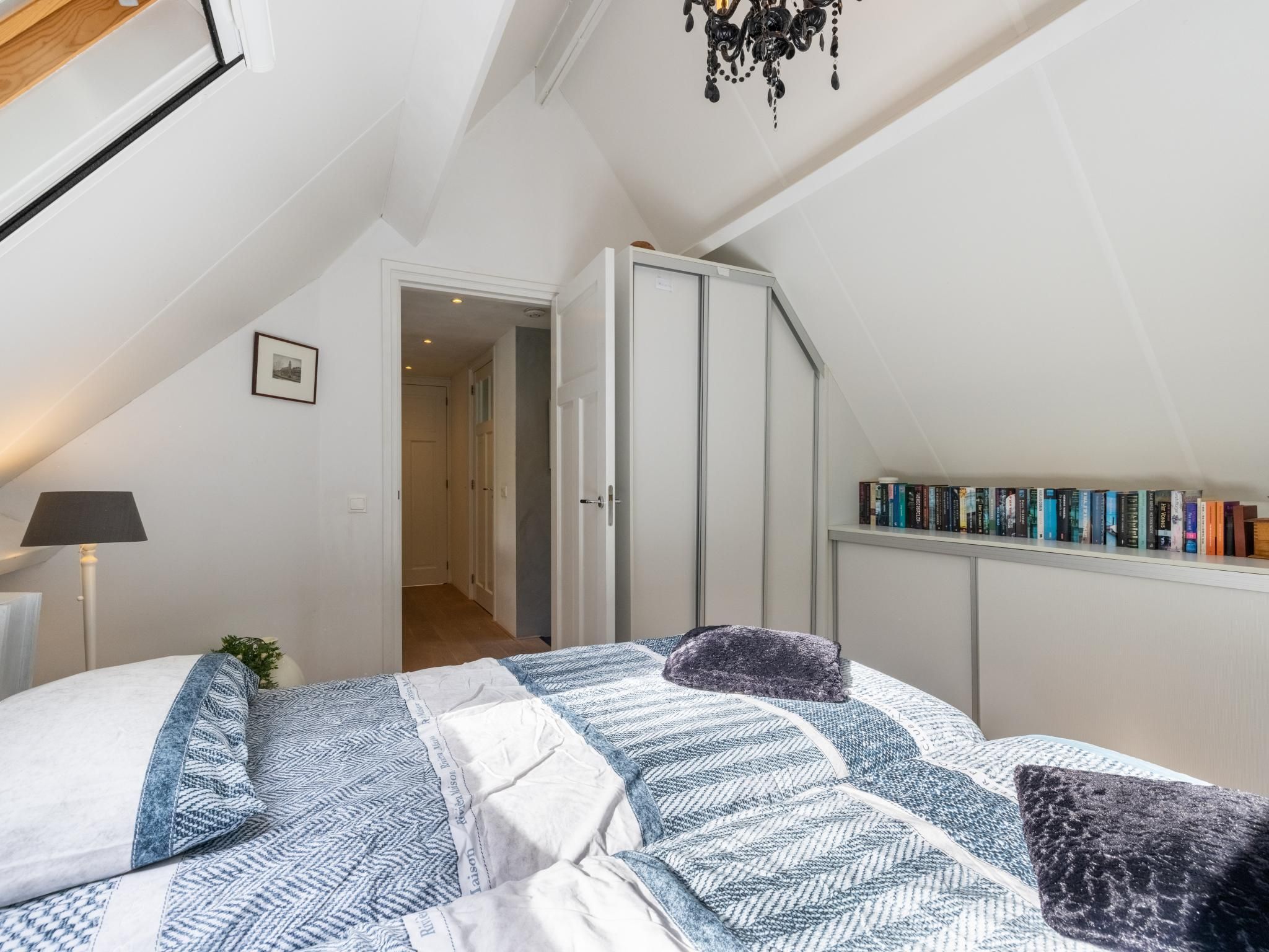 A bedroom with a bed, a bookshelf, and a door leading to another room.