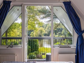 Een kamer met een groot raam met uitzicht op een bebost gebied.