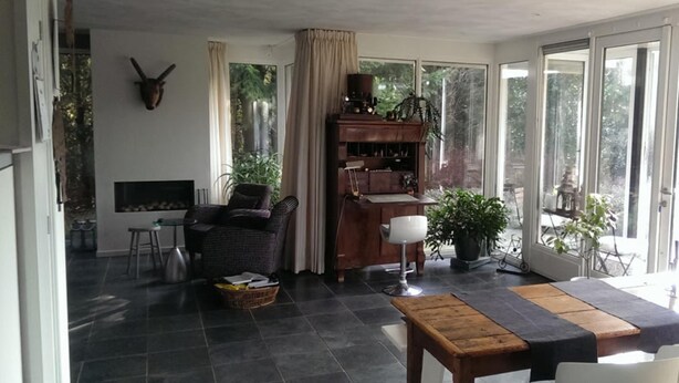 Un amplio salón con chimenea, un sofá, una mesa de comedor y una zona de cocina con cafetera.