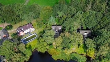 An aerial view of a residential area with multiple houses, a large body of water, and surrounding greenery.