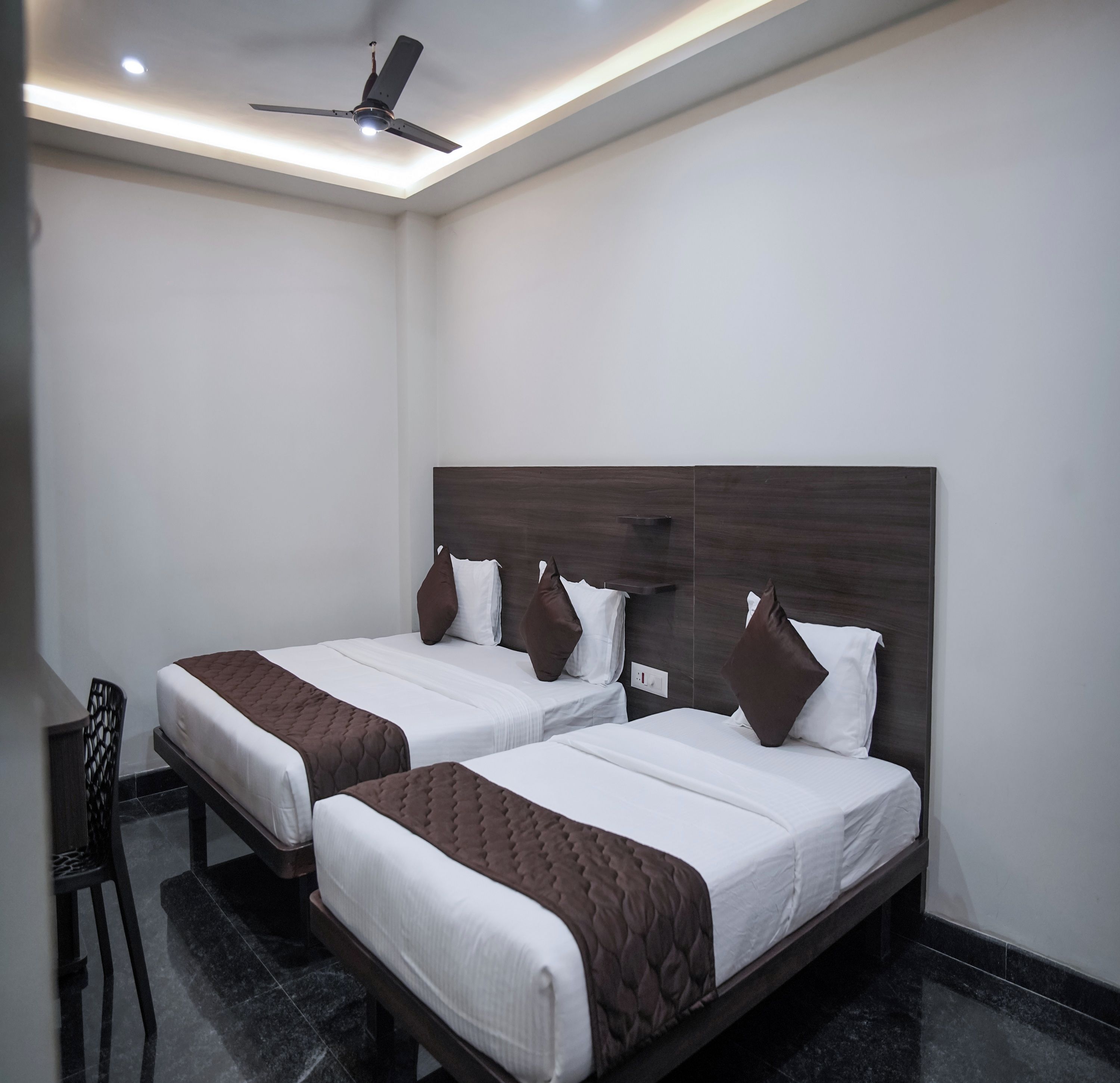 Une chambre d’hôtel avec deux lits, un ventilateur de plafond et une petite table.