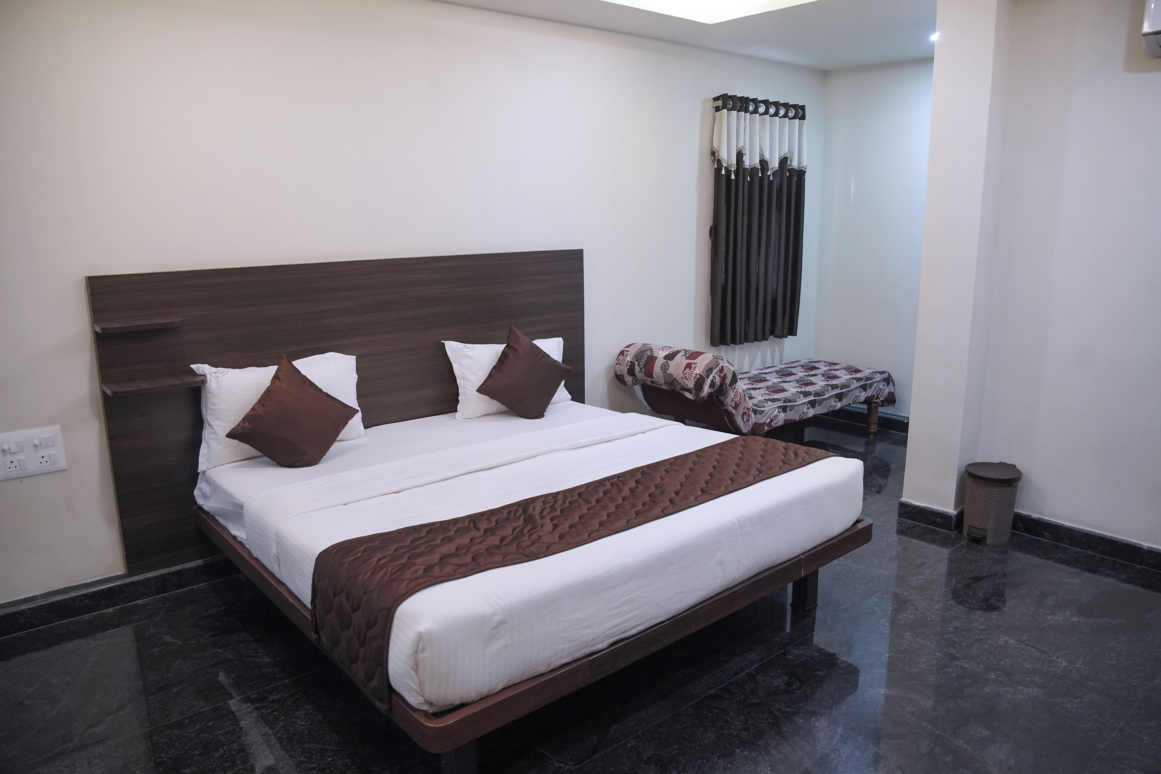 Cama bem arrumada com cabeceira, mesa de cabeceira com capa estampada e ar-condicionado fixado na parede.