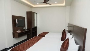 Ein Hotelzimmer mit zwei Betten, einem Fernseher, einem Kleiderschrank und einem Deckenventilator.