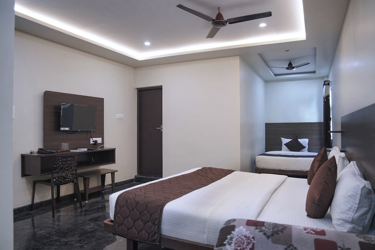 A hotel room with a bed, a desk, a chair, a television, and a ceiling fan.