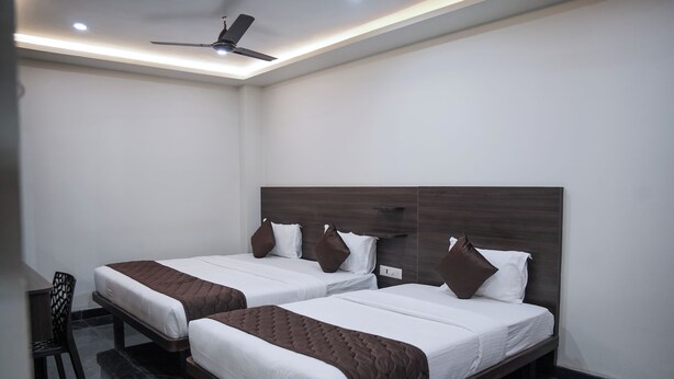 Habitación de hotel con dos camas, un ventilador de techo y una mesita pequeña.