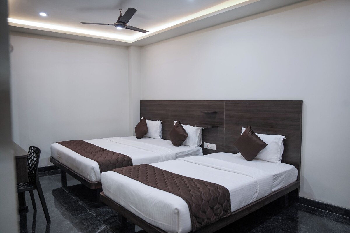 A hotel room with two beds, a ceiling fan, and a small table.