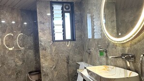 Casa de banho com parede de mármore, sanita, lavatório com espelho e janela.