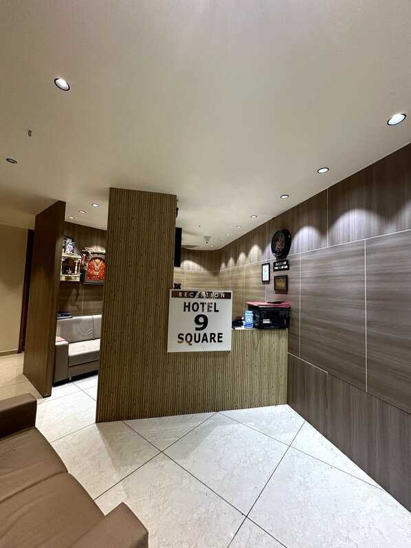 A reception area with a sign indicating 'Hotel 9 Square' and a reception desk.