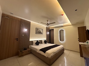 Een moderne hotelkamer met een groot bed, een garderobe, een nachtkastje, een spiegel en een plafondventilator.