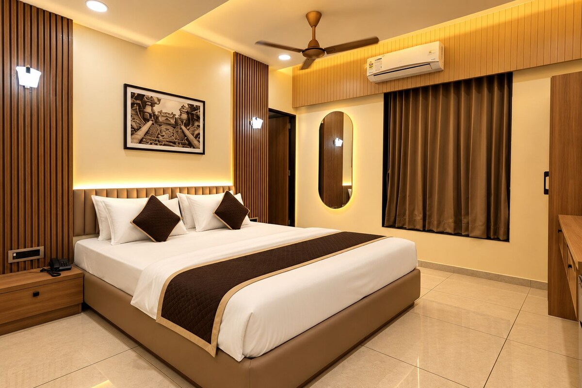 A modern hotel room with a large bed, a ceiling fan, an air conditioning unit, a bedside telephone, and a framed picture on the wall.