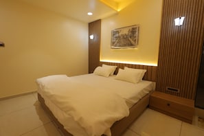 Una camera da letto moderna con un letto grande, una testiera con illuminazione integrata, un comodino e un'opera d'arte appesa al muro.