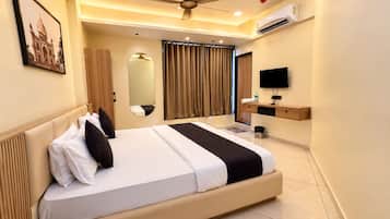 Une chambre d’hôtel avec un grand lit, un ventilateur de plafond, un appareil de climatisation, une télévision et un miroir.