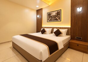 A hotel room with a large bed, a headboard with vertical wooden slats, a wall-mounted picture, and a bedside table with a drawer. - HOTEL 9 SQUARE RAJKOT (Rajkot)