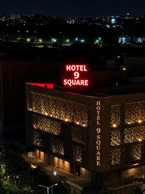 Un edificio con un letrero rojo llamativo que dice 'HOTEL 9 SQUARE' en la parte superior.