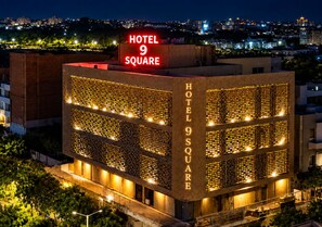 A modern hotel with a prominent sign reading 'HOTEL 9 SQUARE' and a facade featuring a grid-like pattern of lights. - HOTEL 9 SQUARE RAJKOT (Rajkot)