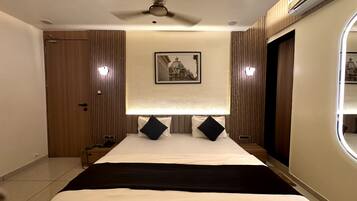 A hotel room with a bed, a ceiling fan, a framed picture on the wall, and a window.