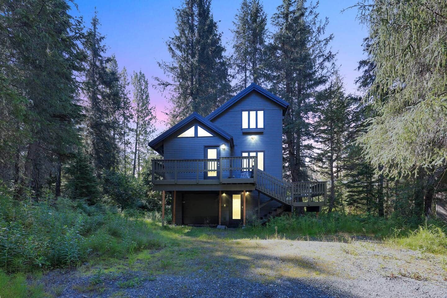 A two-story house with a balcony, surrounded by trees.