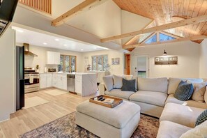 A spacious living area with a sofa set, a kitchen with white cabinets, and a wooden ceiling. - Bright & Stylish Girdwood Home- Ski, Bike, Explore (Anchorage)