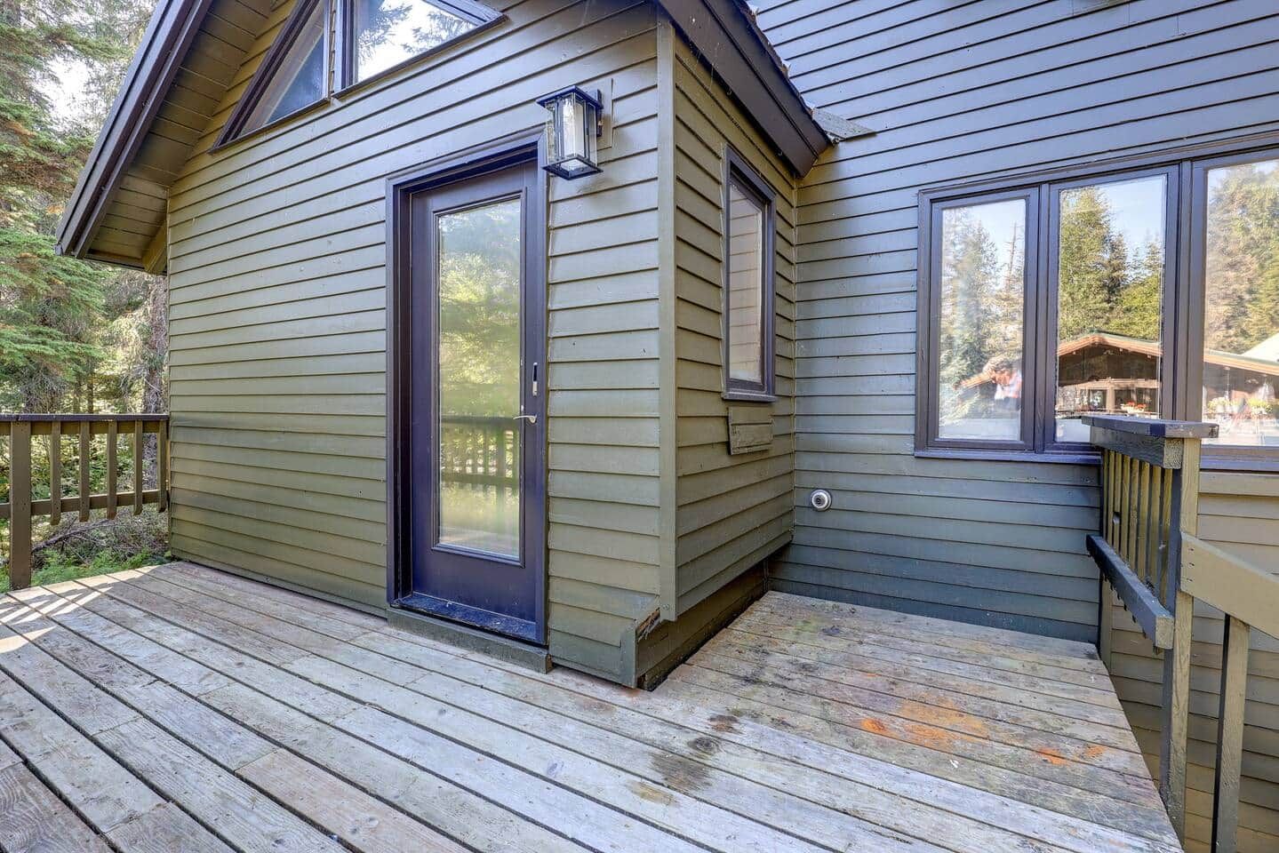 A wooden deck with a sliding glass door leading to a covered porch area.