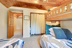 Quarto com beliche, porta que dá para outro cômodo e cortina.