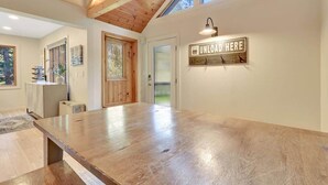 Ein geräumiges Zimmer mit einem großen Holztisch, einer Tür mit Fenster und einem an der Wand befestigten Schild.
