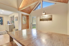 Una habitación amplia con una gran mesa de madera, una puerta con ventana y un letrero en la pared.